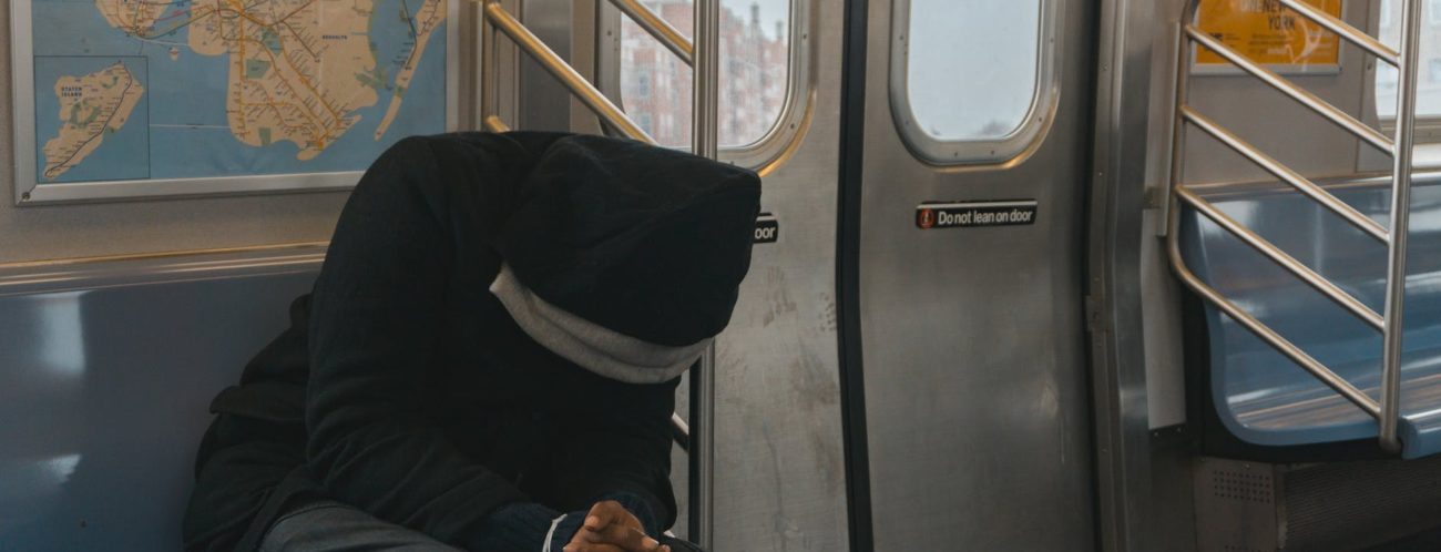 person in black hoodie sitting on train bench