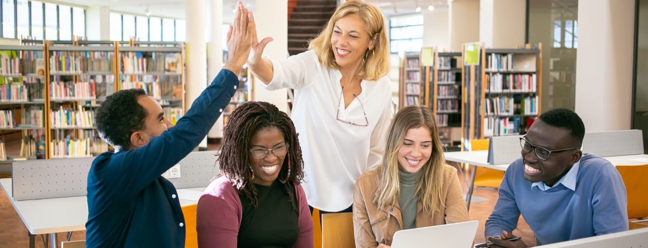 cheerful multiethnic students having high five with teacher