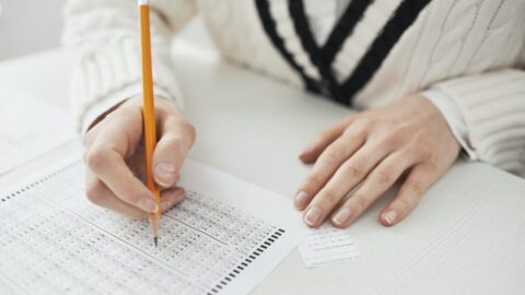a person writing on paper while cheating
